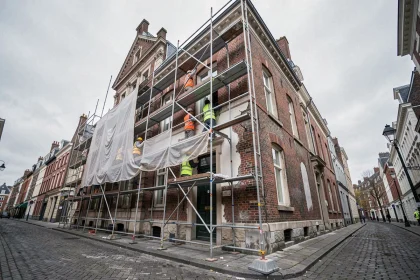 Vue grand angle d'un immeuble à façade de briques flamandes à Lille en cours de rénovation avec des échafaudages et des ouvriers